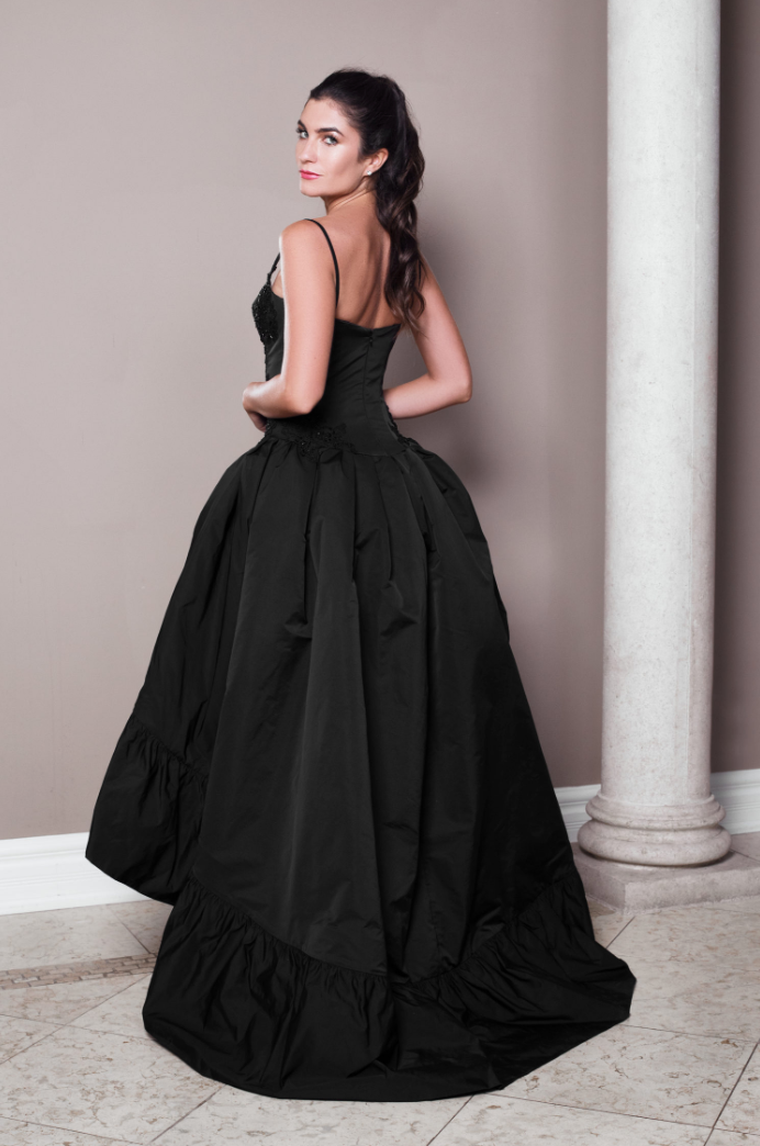 Black silk taffeta high-low ball gown with built-in corset, slender straps, corded and beaded lace appliqué, and dramatic skirt.
