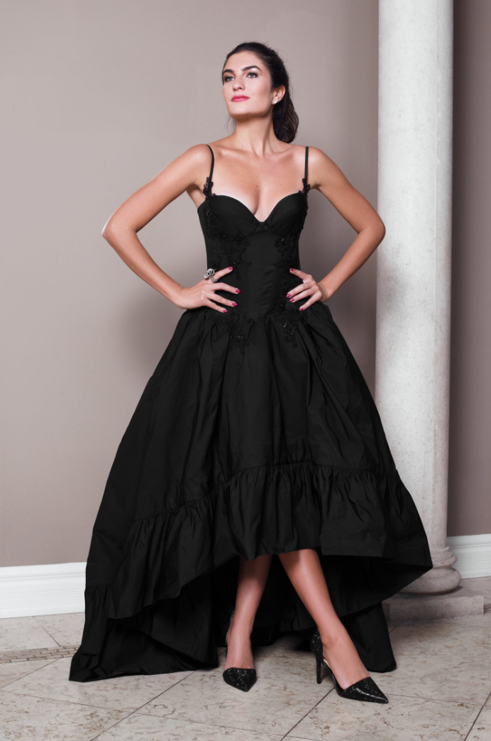 Black silk taffeta high-low ball gown with built-in corset, slender straps, corded and beaded lace appliqué, and dramatic skirt.