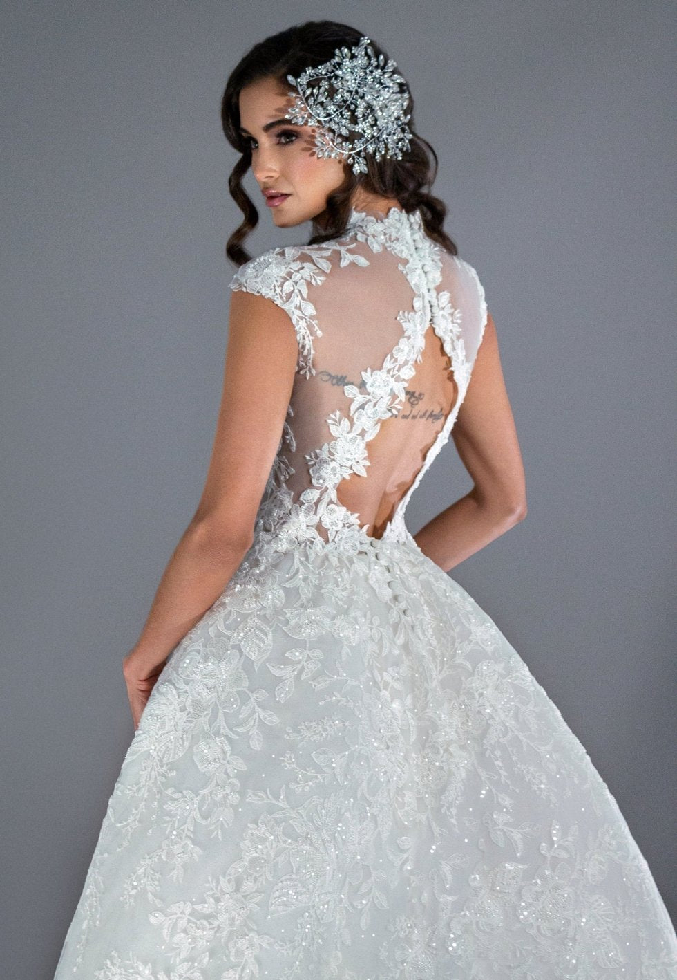 Woman wearing a white lace wedding dress with a gray background