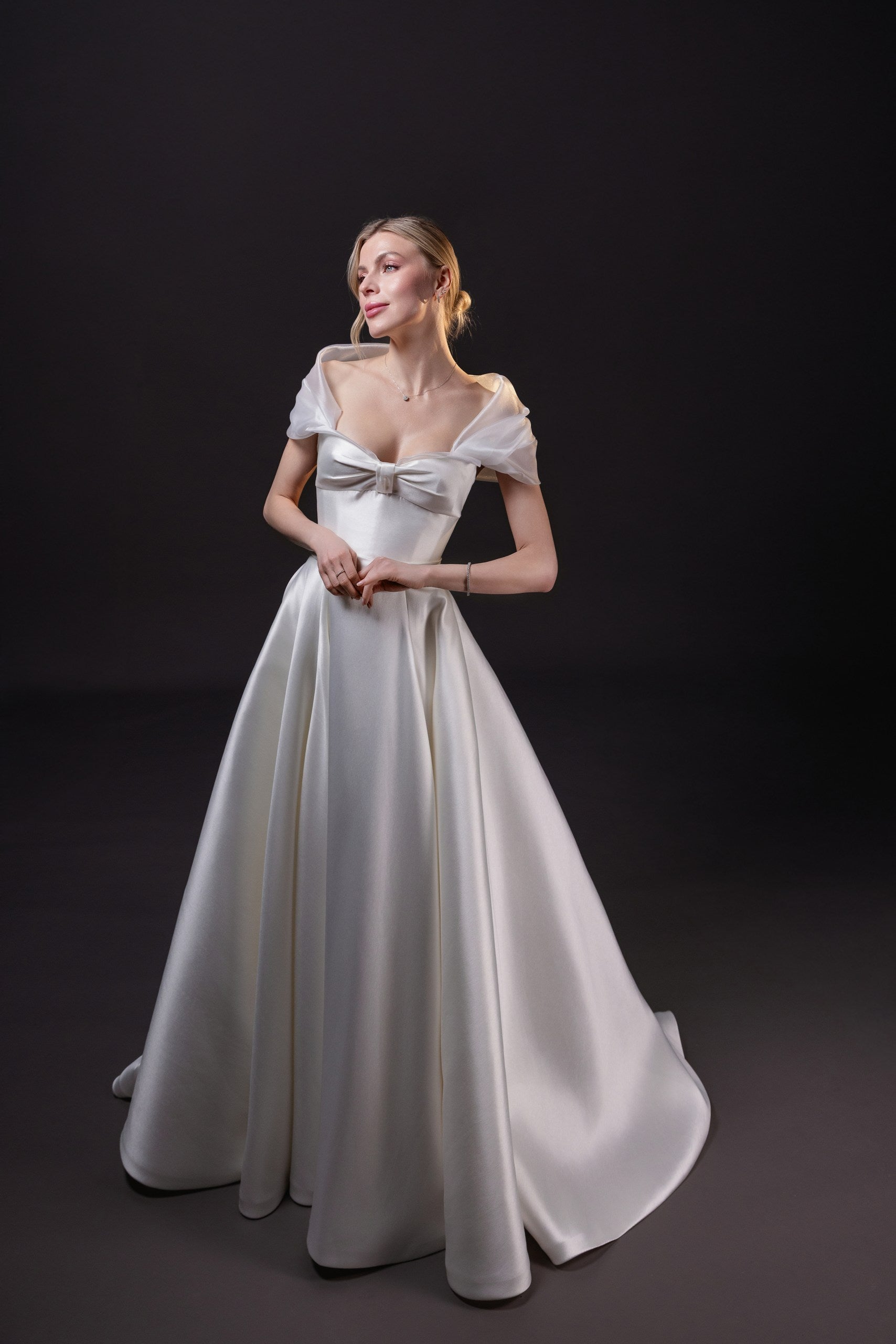 Mirabel silk blend Mikado ball gown with a Basque waistline, bow draped bodice, and full skirt with pockets, Toronto.
