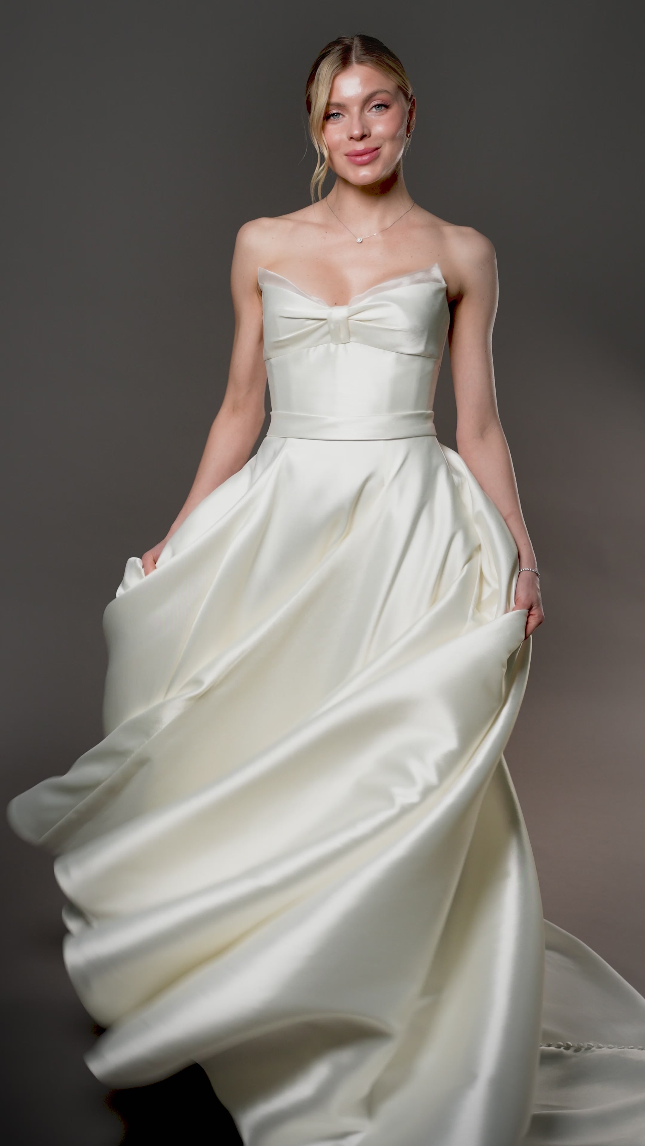 Mirabel silk blend Mikado ball gown with a Basque waistline, bow draped bodice, and full skirt with pockets, Toronto.